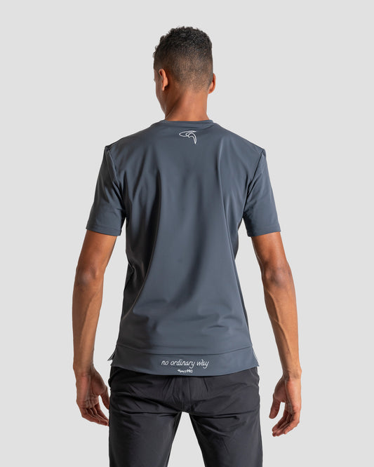 GoofyPRO Cayton Core Performance Tshirt in titanium with short sleeves, rear. White embroidered 'no ordinary way' in white on waistband. White embroidered logo at top of neck. worn by male model