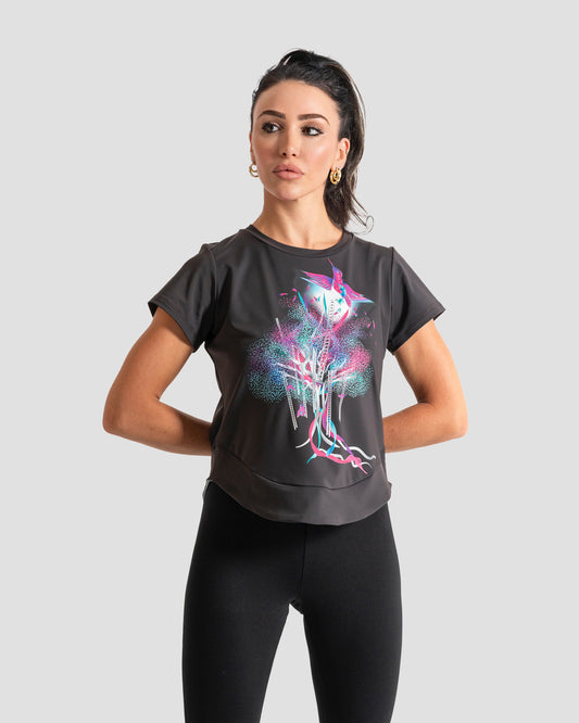 GoofyPRO Cayton Core Performance Tshirt in liquorice with short sleeves. A graphic of a colourful bird flying out of a colourful tree with ribbons. worn by female model